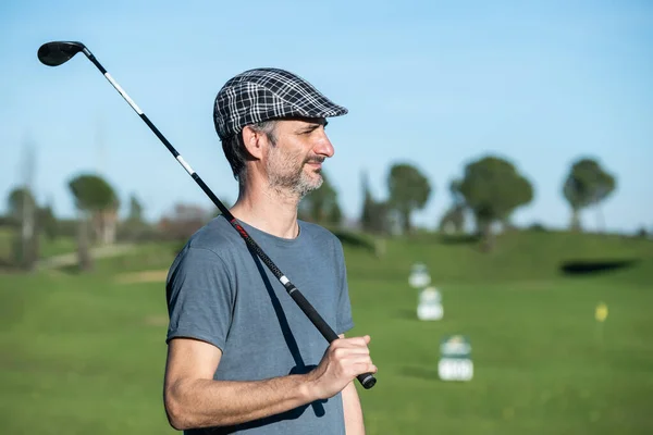 Jugador de golf con gorra y palo sobre su hombro en un campo de conducción — Foto de Stock