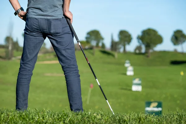 Golfista s čepicí opírající se o golfovou hůl při pohledu na hřiště — Stock fotografie