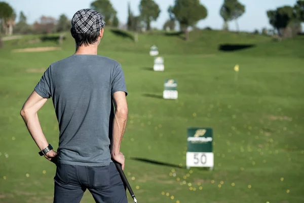 Golf sopasına yaslanmış, ufukta beliren bir golfçü.