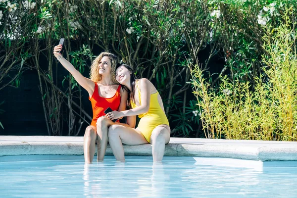 Mulheres de diferentes raças em biquínis tendo sua foto tirada na borda de uma piscina — Fotografia de Stock