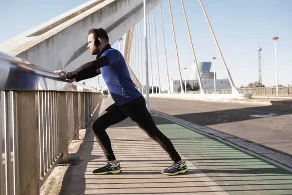 Hombre estirándose sobre una barandilla de puente. concepto deportivo — Foto de Stock