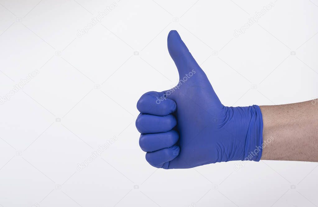 person wearing blue latex gloves with thumb up on white background