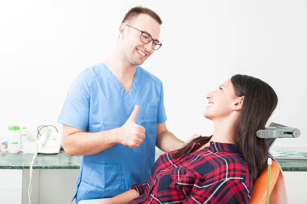 Dentista sorridente mostrando o polegar até seu paciente — Fotografia de Stock