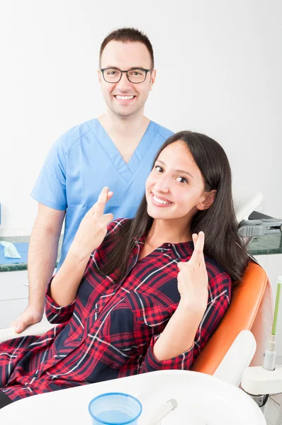 Young lady patient showing fingers crossed on dentist chair — Stock Photo, Image