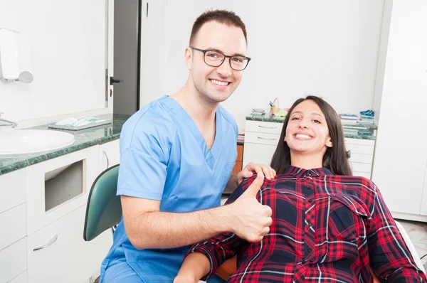Dentista con su paciente sonriendo mostrando el pulgar hacia arriba — Foto de Stock