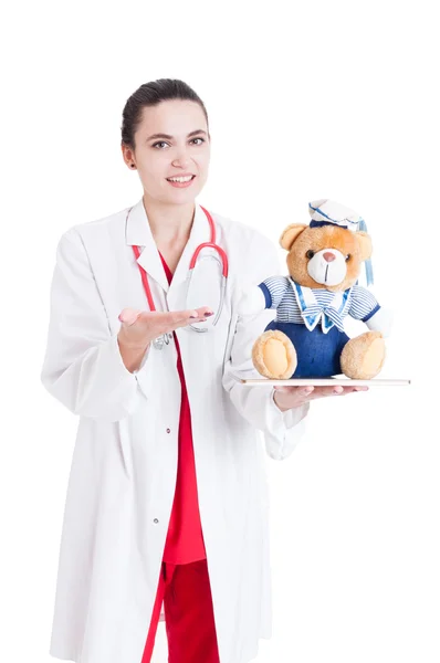 Leende kvinna medic presentera plysch leksak — Stockfoto