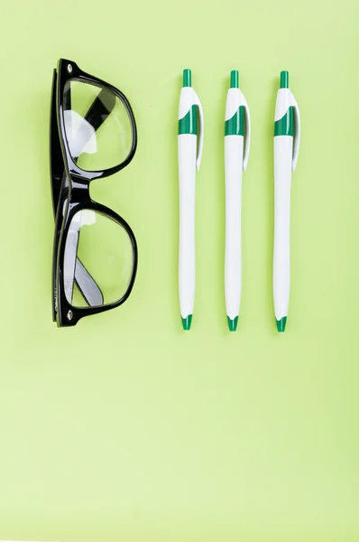 Bovenaanzicht van desktop met bril en pennen — Stockfoto