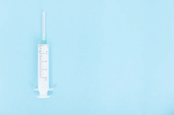 Jedna injekční stříkačka s jehlou na modrém pozadí — Stock fotografie