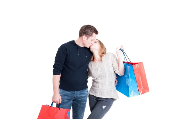 Casal segurando sacos de compras e beijando — Fotografia de Stock