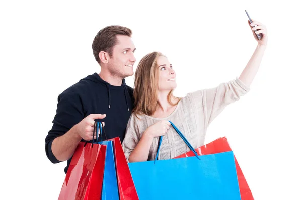 Pareja tomando selfie y sosteniendo bolsas de compras — Foto de Stock