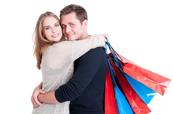 Casal atraente abraçando segurando um monte de sacos de compras — Fotografia de Stock