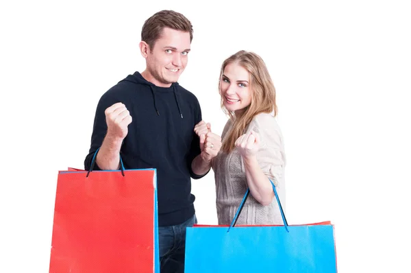 Casal segurando sacos de compras fazendo gesto vencedor — Fotografia de Stock