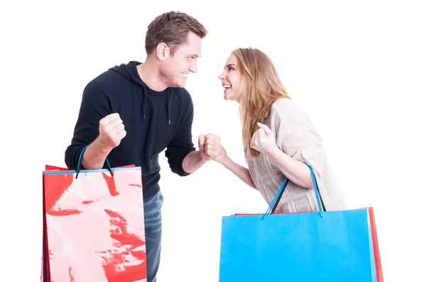 Pareja sosteniendo bolsas de compras haciendo que el gesto ganador se sienta feliz —  Fotos de Stock