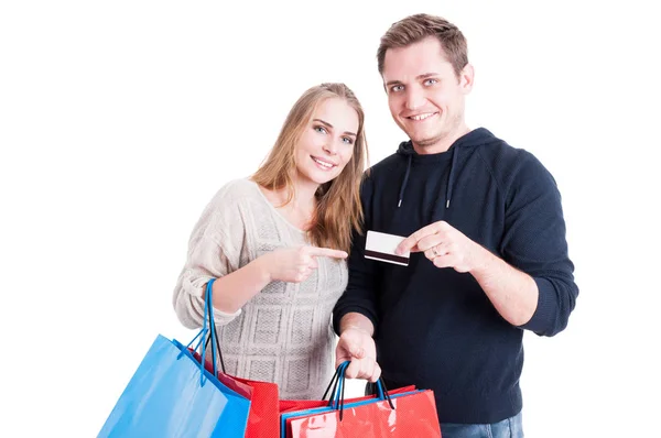 Pareja sosteniendo bolsas de compras apuntando con tarjeta de crédito —  Fotos de Stock