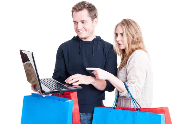 Pareja sosteniendo bolsas de compras y mirando en el ordenador portátil —  Fotos de Stock