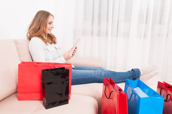 Smiling woman shopper holding tablet laying on couch — Stock Photo, Image