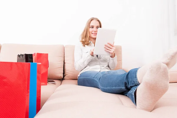 Donna sorridente shopper tenendo tablet posa sul divano — Foto Stock