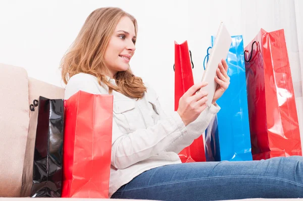Женщина улыбается и ходить по магазинам онлайн с сумками вокруг — стоковое фото