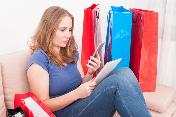 Woman sitting on couch holding smartphone and tablet — Stock Photo, Image