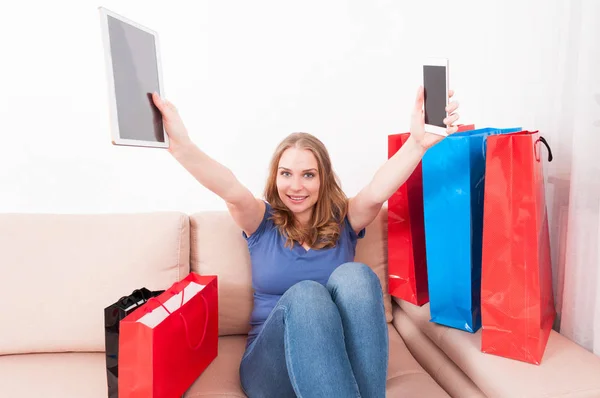 Mujer atractiva sosteniendo la tableta y el teléfono inteligente actuando feliz —  Fotos de Stock