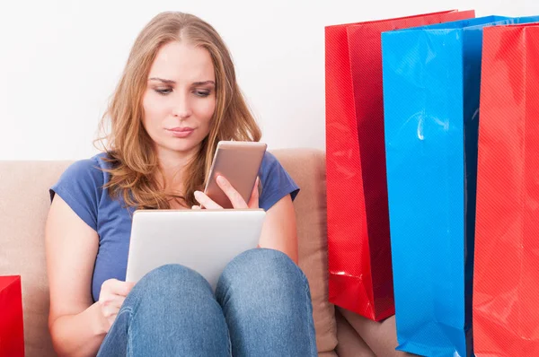 Mujer de compras en casa sosteniendo teléfono inteligente y tableta —  Fotos de Stock