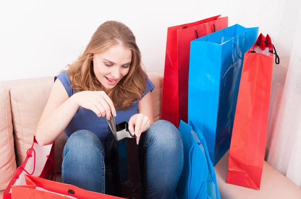 Lady sitting on couch finding necklace in shopping bags — Stock Photo, Image