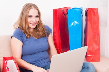 Online sipariş verme gibi gülümseyen kanepede oturan kadın 