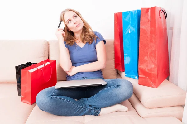 Женщина, сидящая на диване, подумывает сделать онлайн заказ — стоковое фото