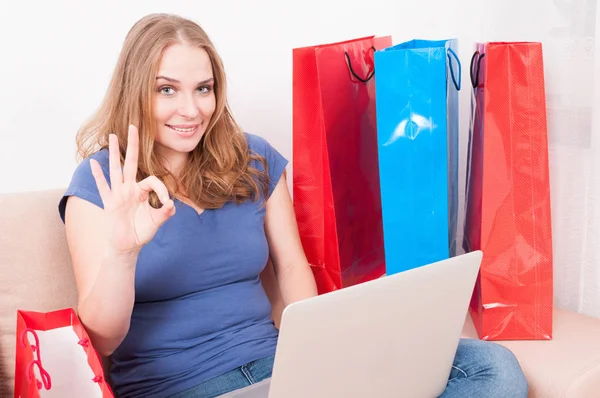 Woman sitting on couch making online order showing okay — Stock Photo, Image