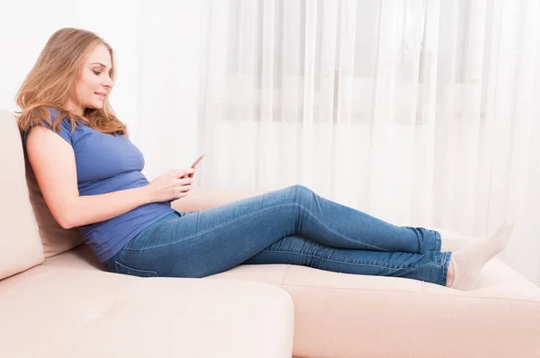 Senhora sentada no sofá mensagens de texto no smartphone — Fotografia de Stock
