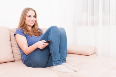 Uzaktan kumanda tutan kanepede oturan kadın