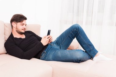 Adam akıllı telefon ve mesaj atıp tutarak kanepenin üzerinde döşeme