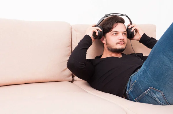 Man laying on sofa putting on headphones