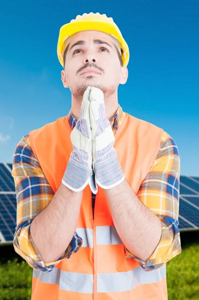 Man standing by solar panels and praying — Stock Photo, Image