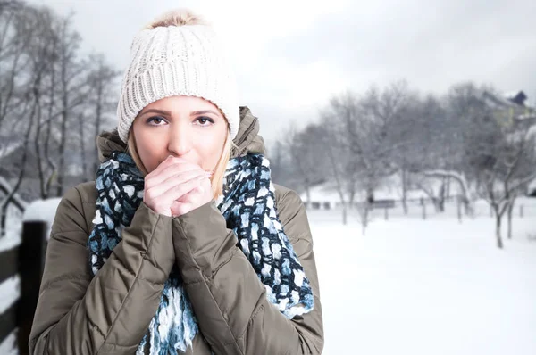 Зимняя девушка, дующая на свои руки — стоковое фото