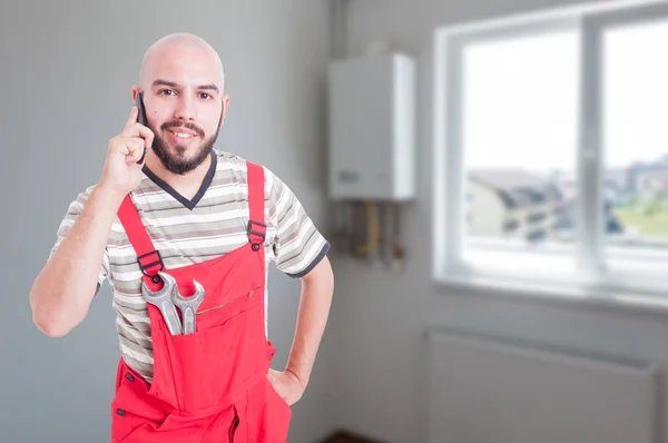 Upptagen montör i arbetsutrustning som talar på mobiltelefon — Stockfoto