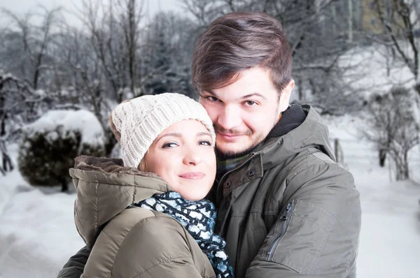 Uśmiechający się para i przytulanie siebie w zimowym lesie — Zdjęcie stockowe