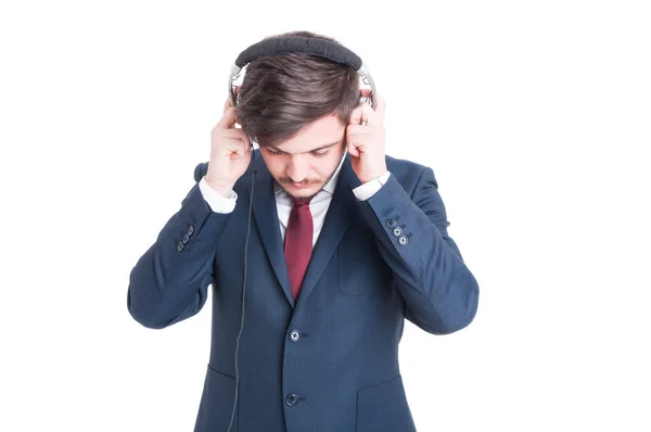 Hombre de negocios de pie mirando hacia abajo y poniéndose auriculares — Foto de Stock