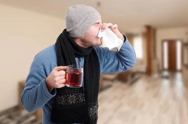 Чоловік п'є гарячий чай і протирає ніс — стокове фото