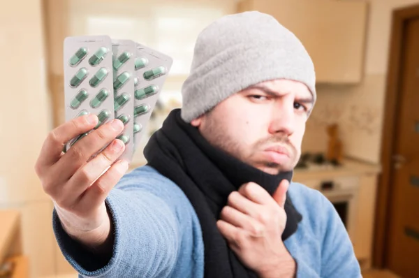 Homem doente com tiras de comprimidos na mão — Fotografia de Stock