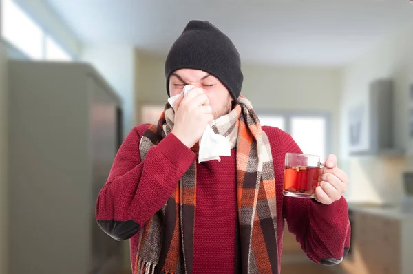 病気の男のティーカップを押しながら鼻をかむ — ストック写真
