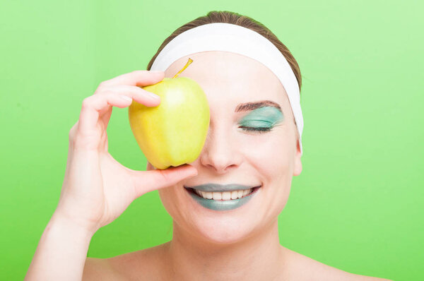 Young woman covering her eye with an apple