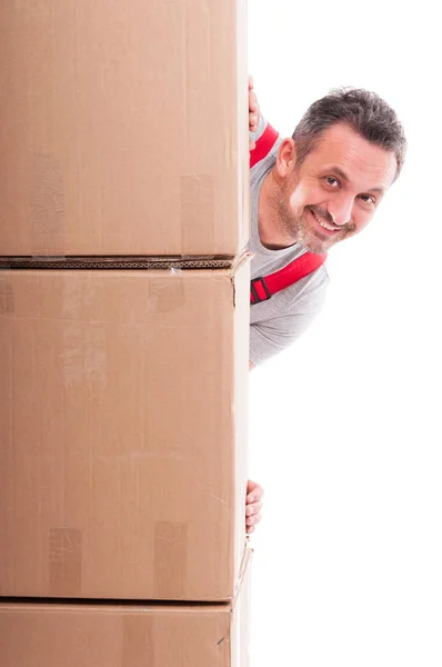 Smiling guy hiding being pile of cardboard boxes — Stock Photo, Image