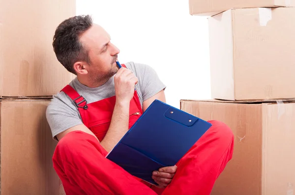 Mover guy sitting holding clipboard and thinking — Stock Photo, Image
