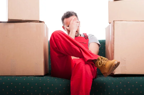 Tired mover man sitting on couch with cardboard boxes around — Stock Photo, Image