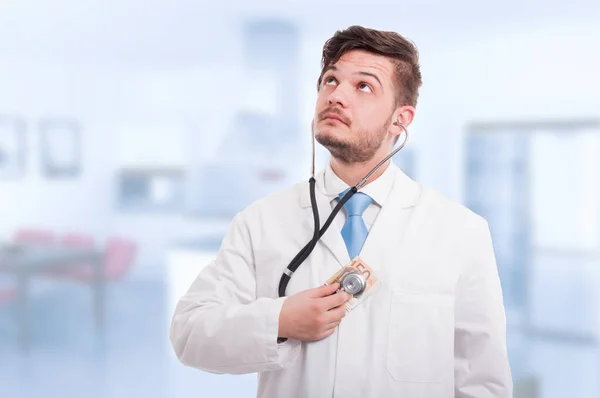 Doctor holding money and listening heart with stethoscope — Stock Photo, Image