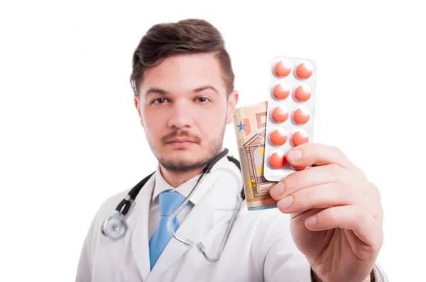 Píldoras y dinero en la mano del médico — Foto de Stock