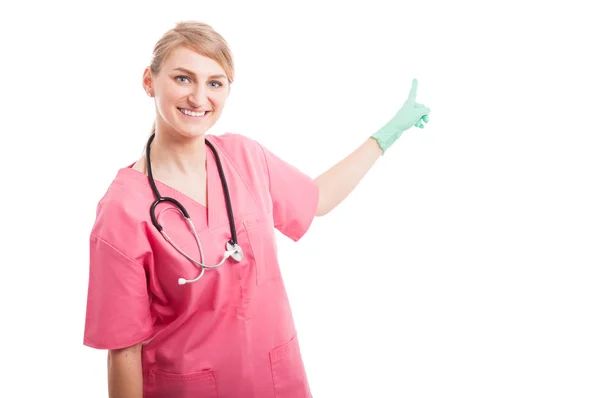 Friendly medical nurse lady smiling pointing copyspace — Stock Photo, Image