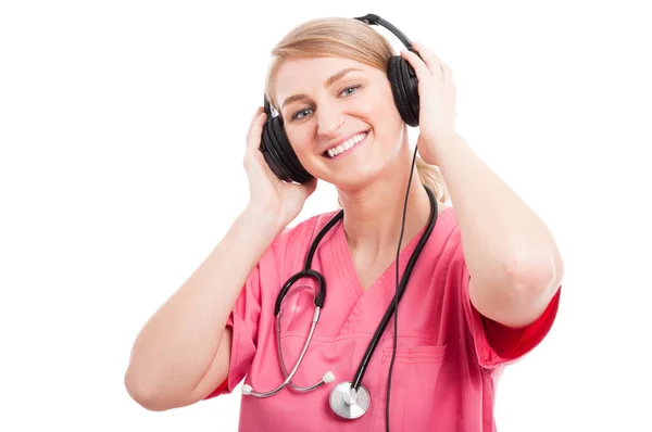 Female nurse wearing scrubs listening to headset — Stock Photo, Image