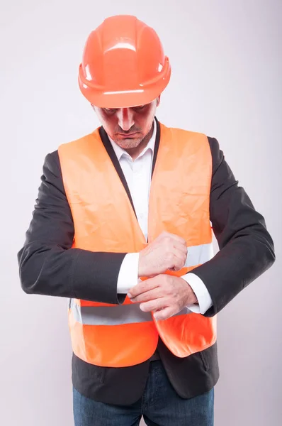 Contractor wearing hardhat and reflective vest arranging his shi — Stock Photo, Image